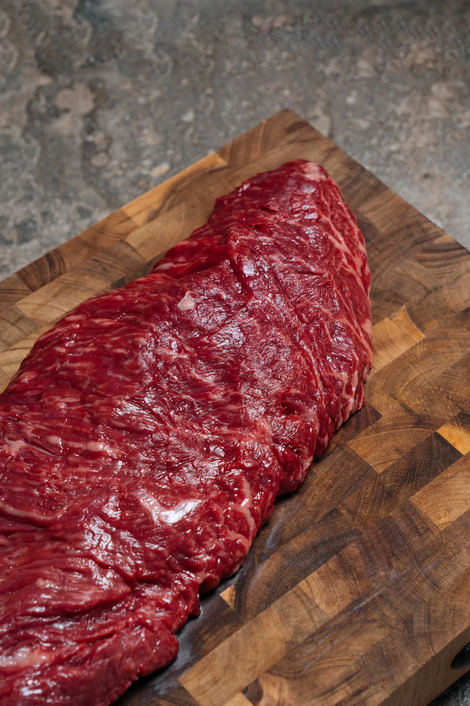 Een rauwe bavette van Tajiri op een snijplank van kopshout
