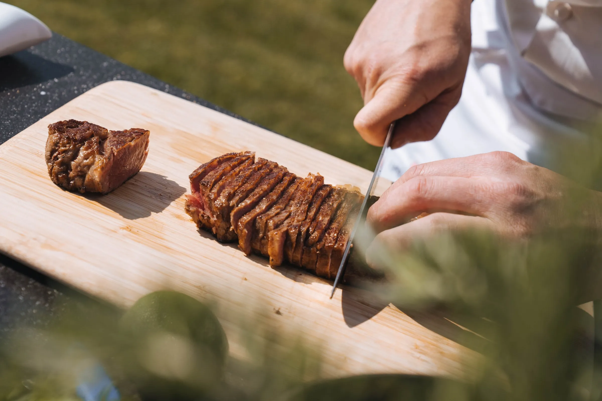 Een chef snijdt een gebakken steak van Tajiri in tranches op een houten plank